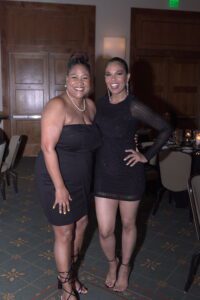 Two women in black dresses posing for a picture.