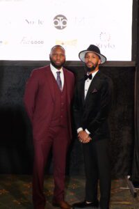 Two men in suits and hats posing for a picture.