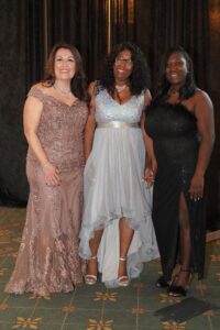 Three women in dresses posing for a picture.