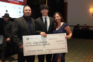 Three people holding a large check in front of them.