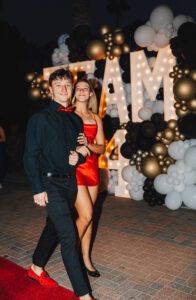 A man and woman walking in front of balloons.