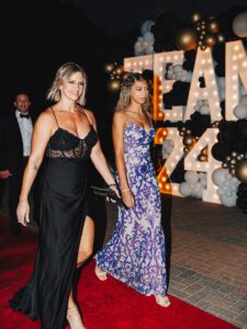 Two women in dresses walking on a red carpet