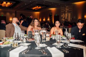 A group of people sitting at tables with wine glasses.