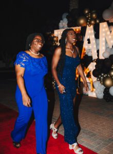 Two women walking in front of a wall with balloons.