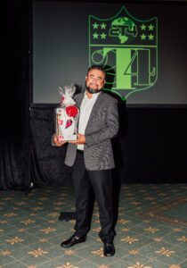 A man holding a trophy in front of a green screen.