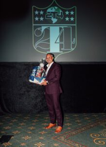 A man in a suit holding a box of beer.