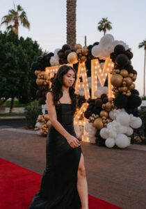 A woman in black dress standing on red carpet.