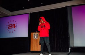 A man in red hoodie standing on stage.