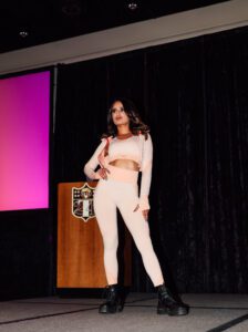 A woman in white outfit standing on stage.