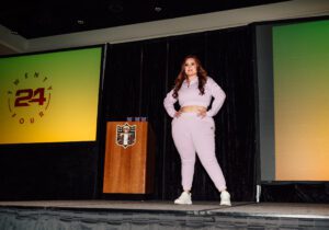 A woman in pink pants and white shoes on stage.