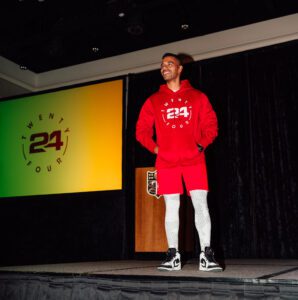 A man in red hoodie standing on stage.