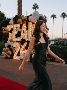 A woman in black dress walking on the red carpet.