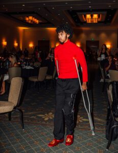 A person with crutches standing in front of a crowd.