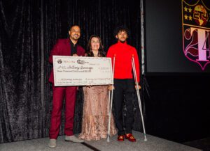 A group of people standing on stage holding up a large check.