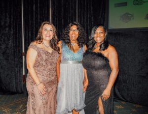 Three women in dresses posing for a picture.