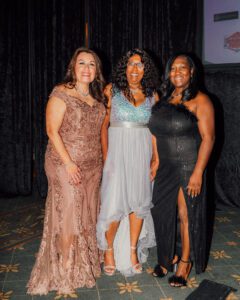 Three women in dresses posing for a picture.