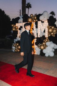 A man in black suit walking on the red carpet.