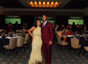 A man and woman posing for the camera in formal wear.