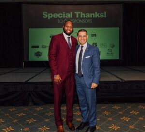 Two men in suits posing for a picture.