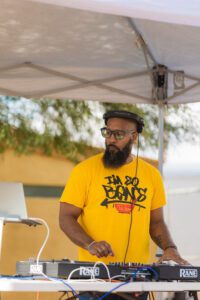 A man in a yellow shirt standing under an awning.