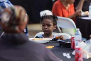 A young girl sitting at the table eating food.