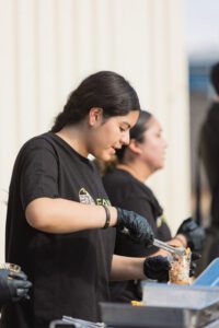 A woman in black shirt holding a knife.