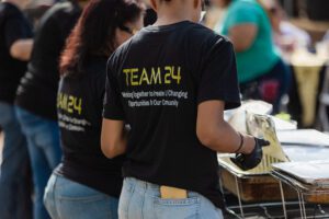 A man and woman wearing team 2 4 shirts.