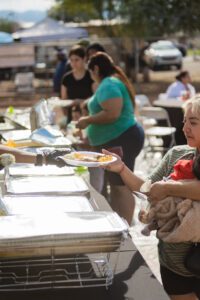 A woman holding a baby in her arms at an outdoor buffet.