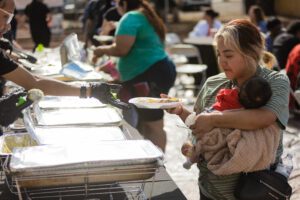 A woman holding her baby at the buffet line.