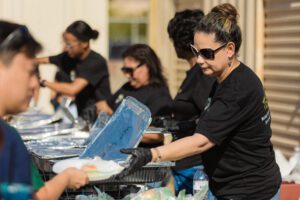 A woman is serving food to someone at the table.