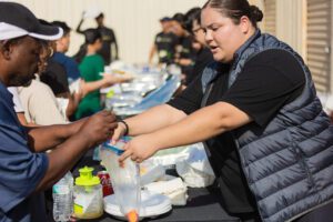 A woman is handing out food to people.