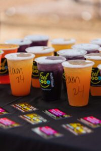 A table with several cups of juice and cans.