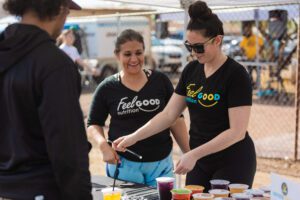 Two women and a man are standing at an outdoor table.