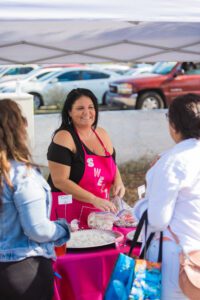 A woman in an apron is serving food to people.