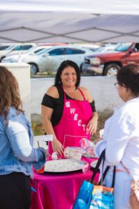 A woman in pink apron holding a cake.