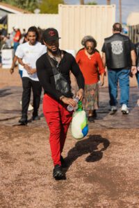 A man in red pants and black shirt holding a bag.