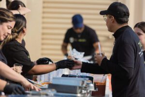 A man in black shirt holding food near two other men.