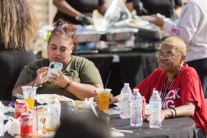 Two women sitting at a table with drinks and food.