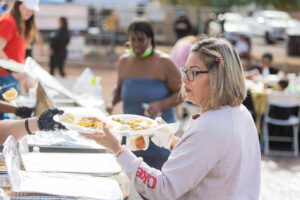 A woman holding a plate of food at an outdoor event.