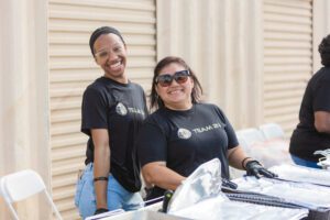 Two women in black shirts smiling for a picture.