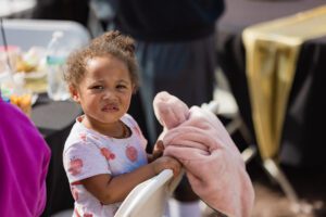 A little girl holding onto a pink teddy bear.