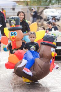 A child sitting on an inflatable turkey.