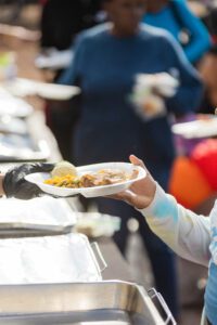 A person holding food in their hand at an outdoor event.