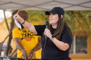 A woman holding a microphone and wearing a hat.