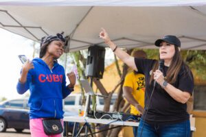 Two women are singing in front of a microphone.