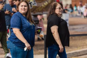 Two women standing next to each other on a street.