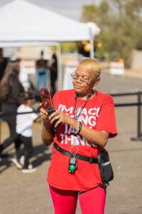 A woman in red shirt holding up a cell phone.