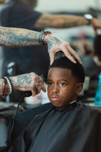 A boy getting his hair cut by an adult.