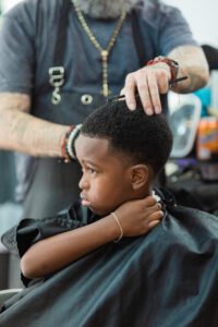 A young boy getting his hair cut by an adult.