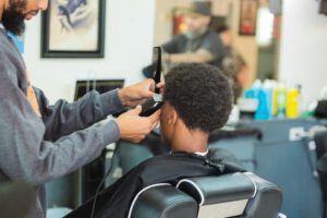 A man getting his hair cut by another person.